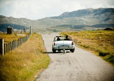 a couple driving away together in a convertible car on their wedding day