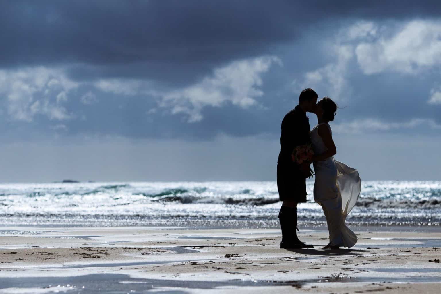 Janet-and-Craig—Isle-of-Lewis a couple are silhouetted against the sea on their wedding day on the isle of lewis