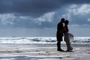 a couple are silhouetted against the sea on their wedding day on the isle of lewis