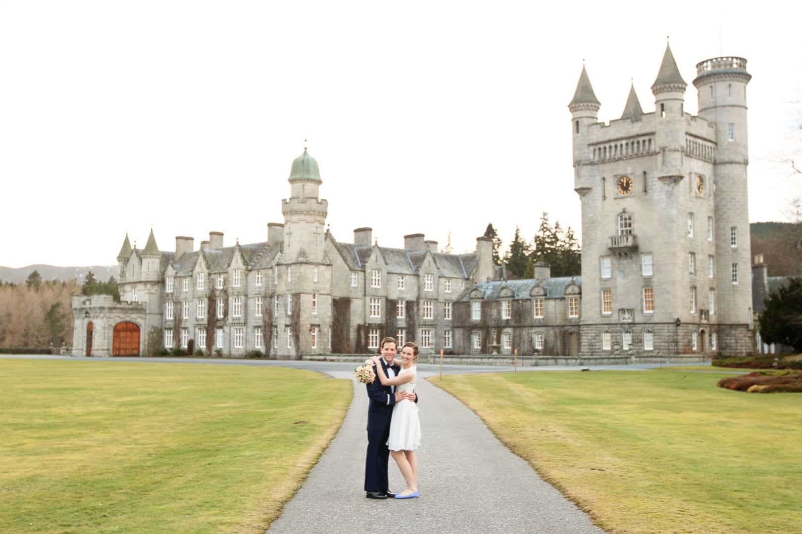 a bride and groom standing outside balmoral castle in aberdeenshire