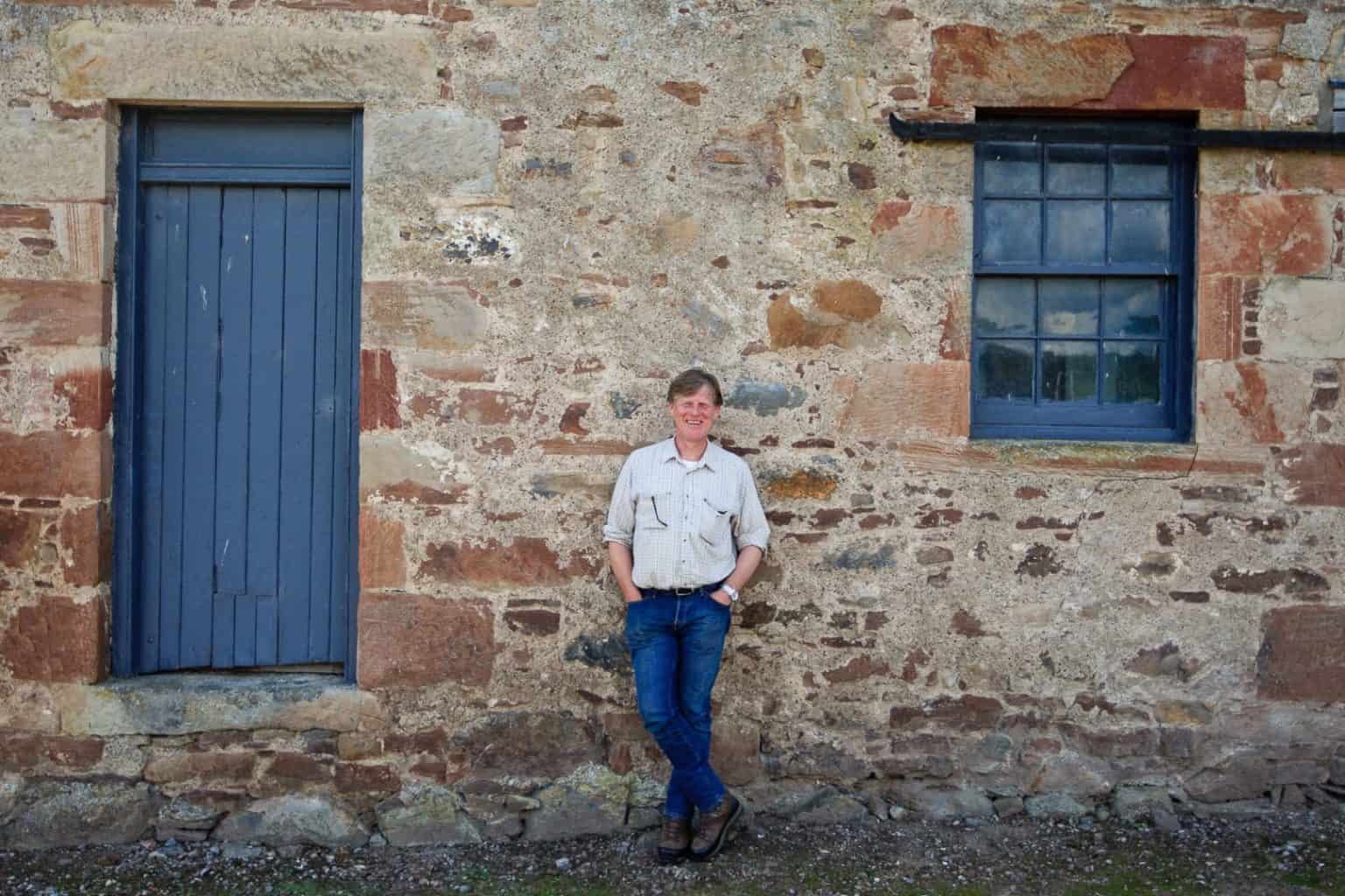 kjeld kristensen, christmas tree farmer leans against a wall.