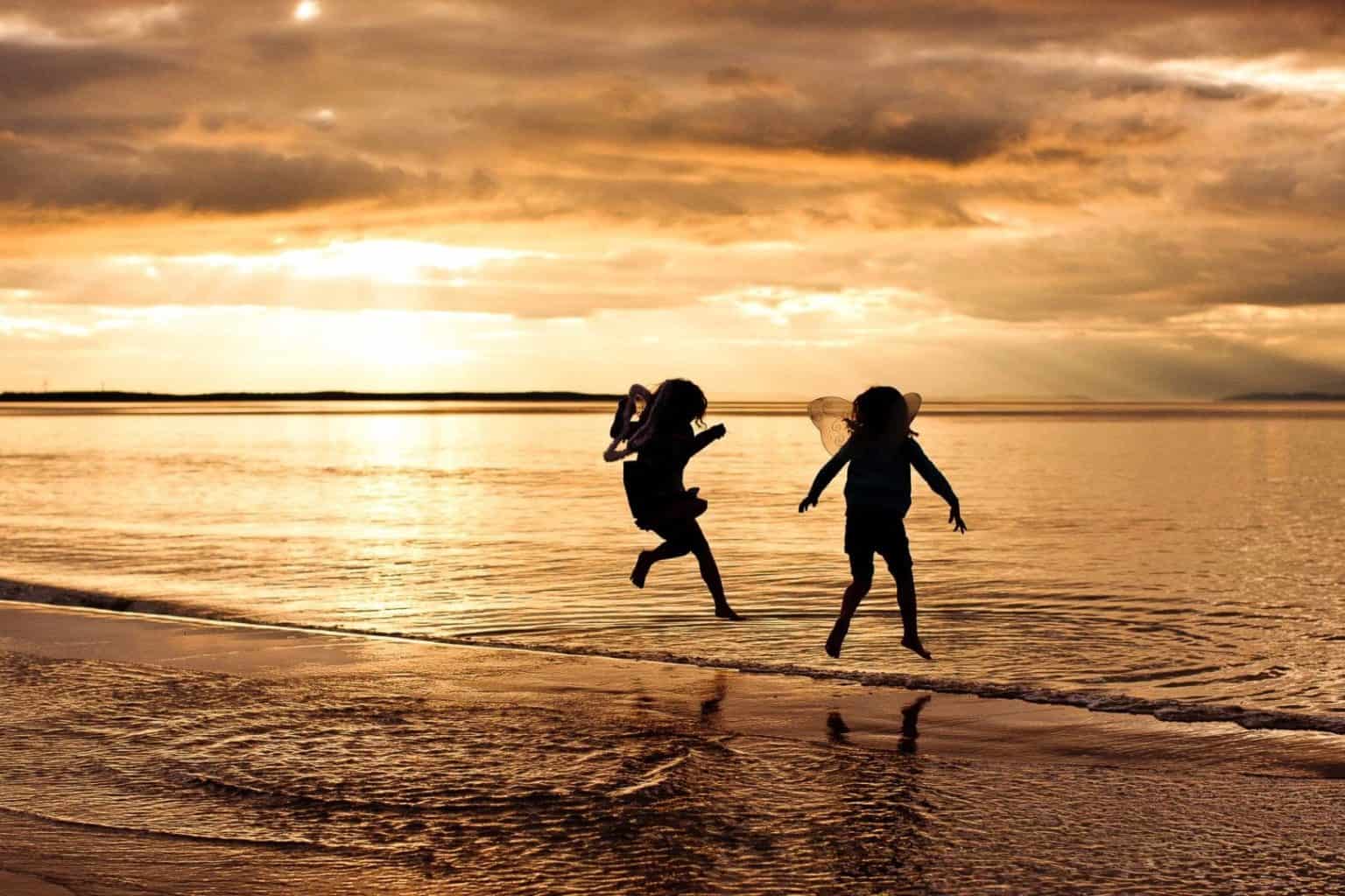 elgin-family-photographer girls dressed up as fairies jump into the sea during their family portrait session