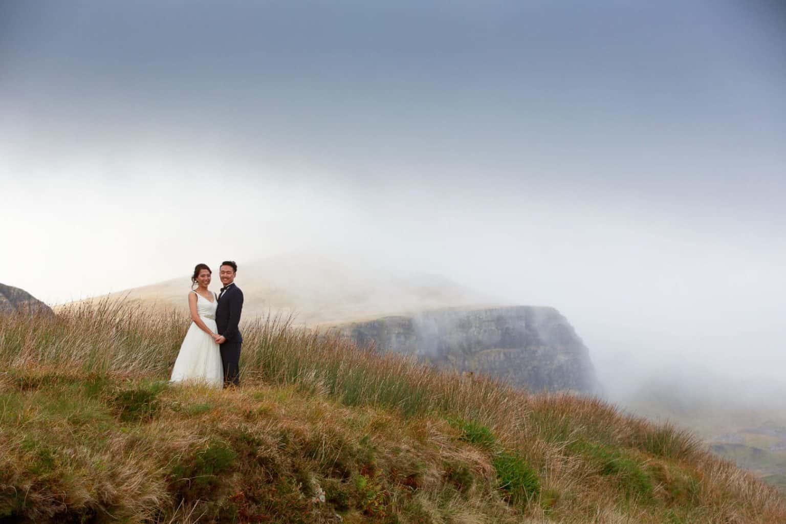 elopement-wedding-on-the-isle-of-skye-tscottish-highlands a bride and groom stand next to the old man of storr on their elopement to scotland