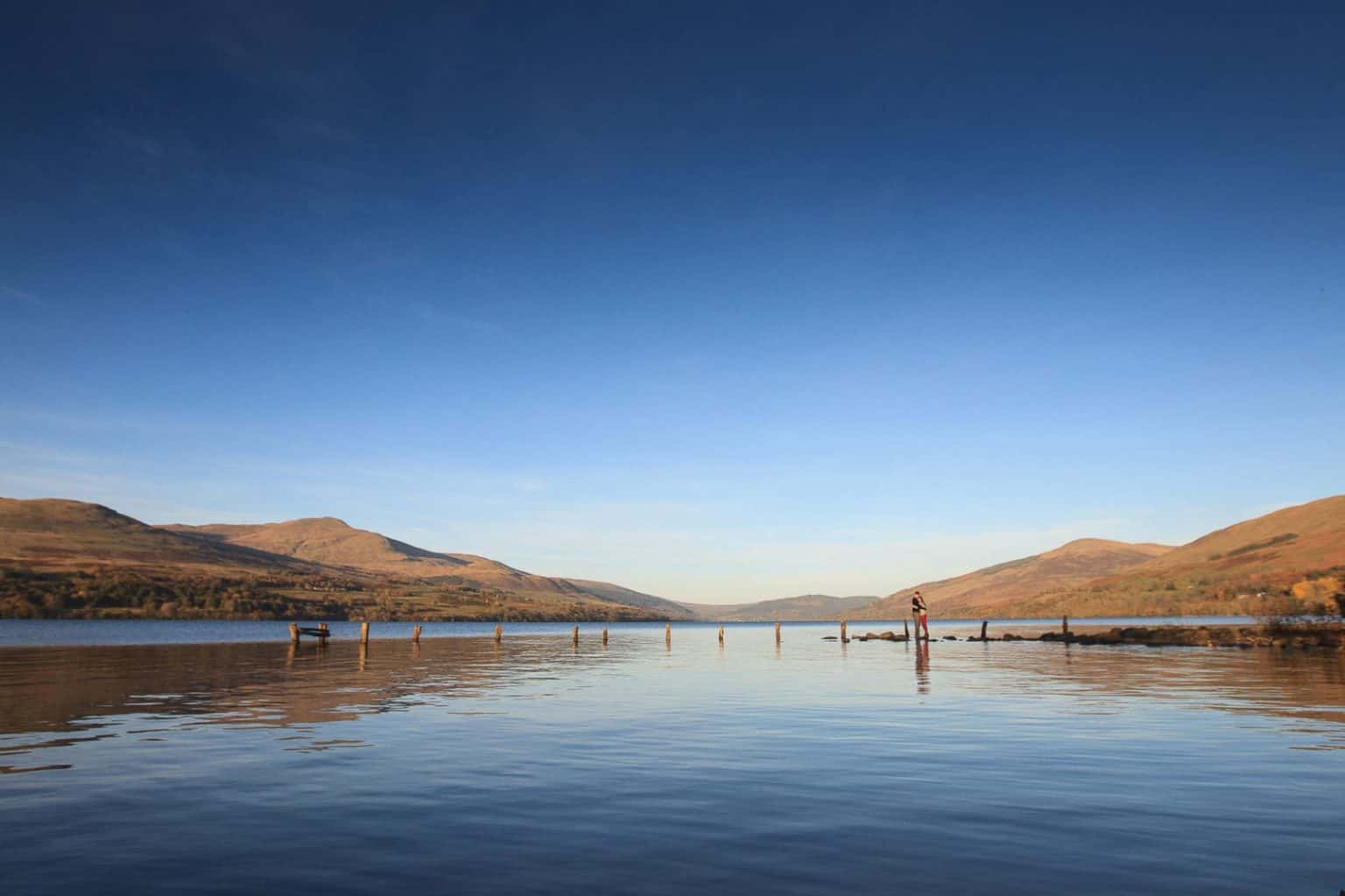 engagement-photography-scotland-2 a newly engaged couple stand on rocks on the banks of loch tay