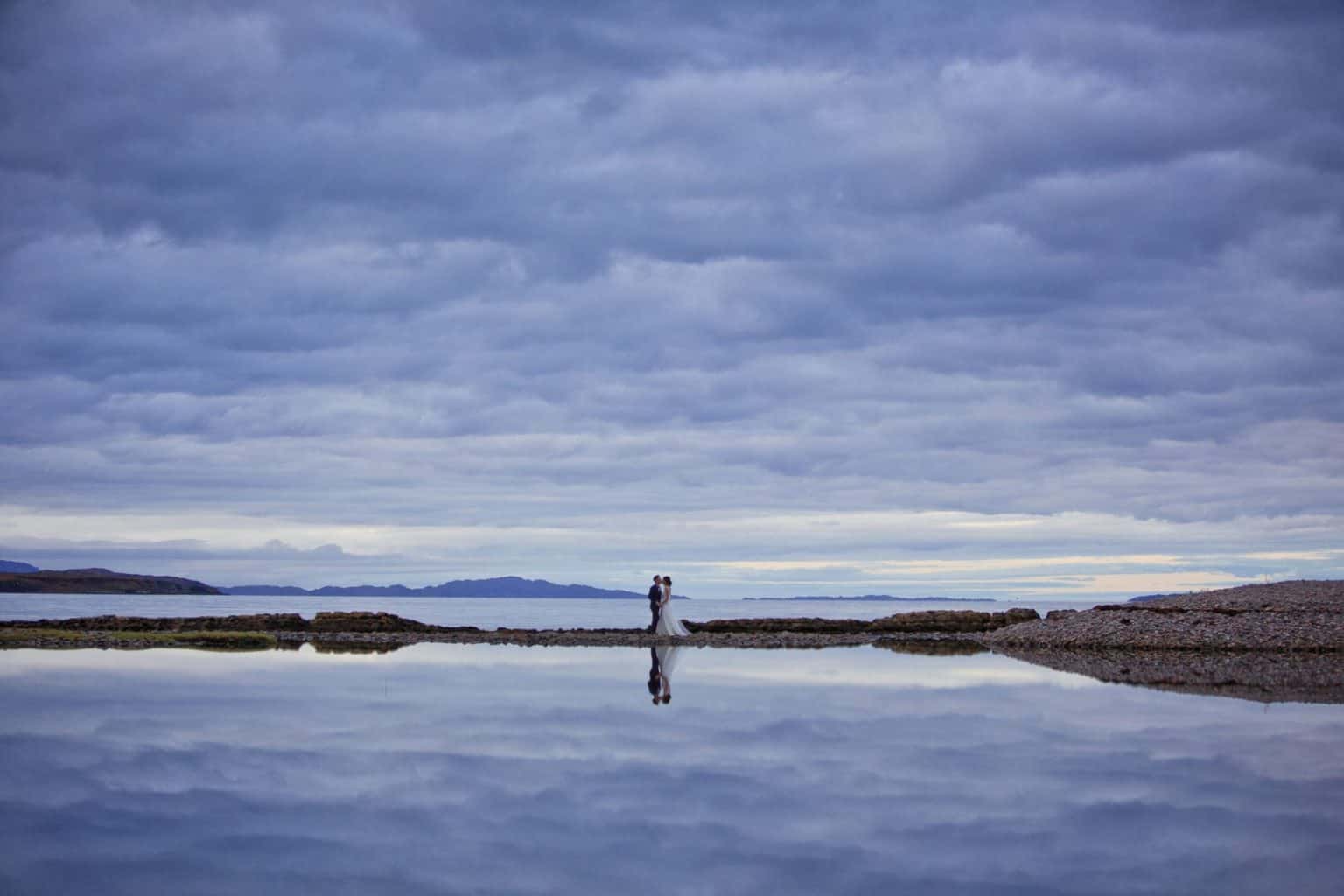 isle-of-skye-wedding-photographer a bride and groom are reflected off the water