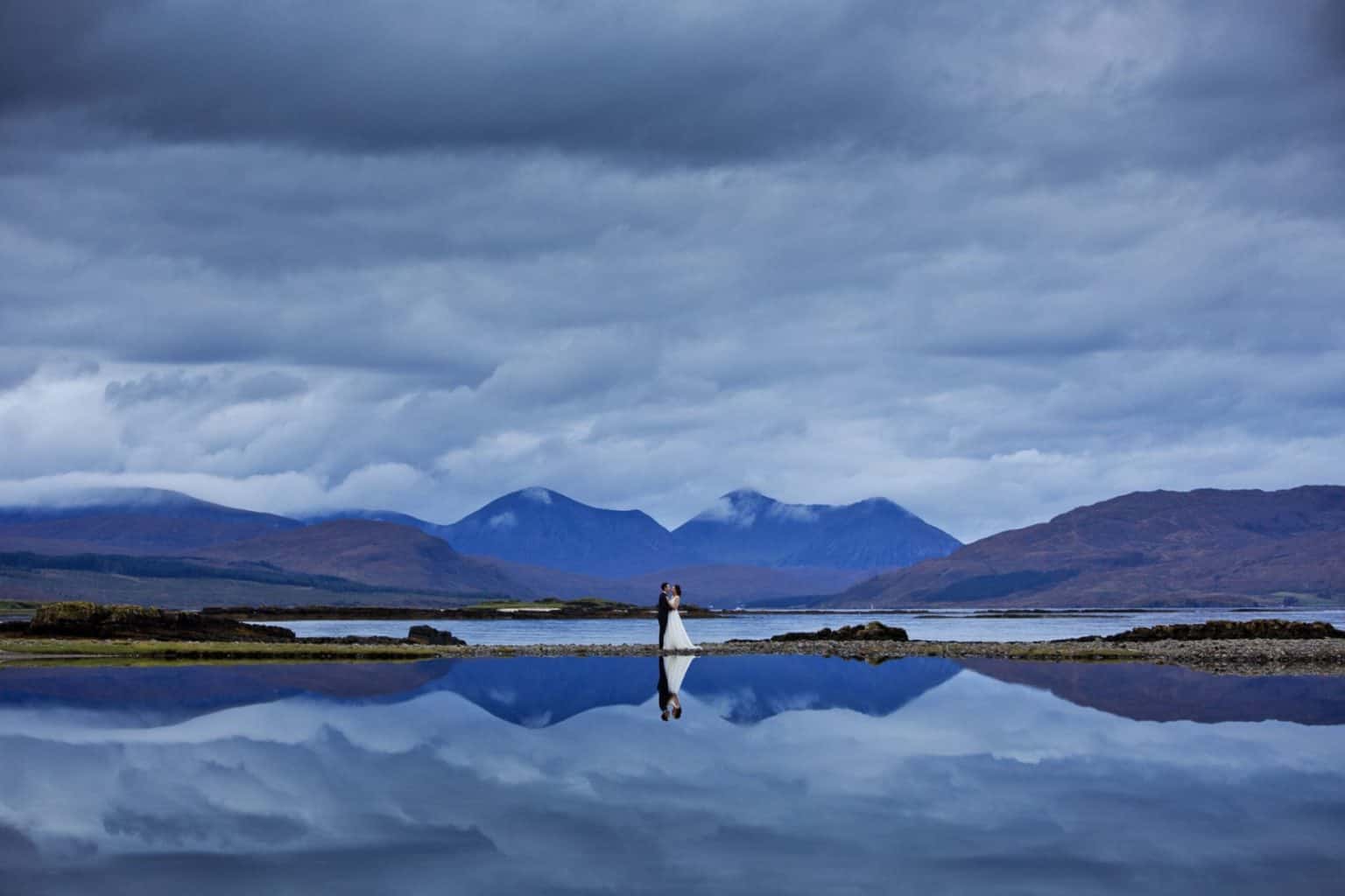 isle-of-skye-wedding-photography a bride and groom are reflected off the water along with the cuilin hills on the isle of skye