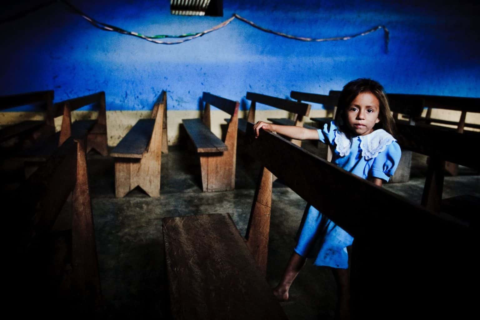 peruvian-girl-travel-portrait a young girl sits on a pew in a blue church