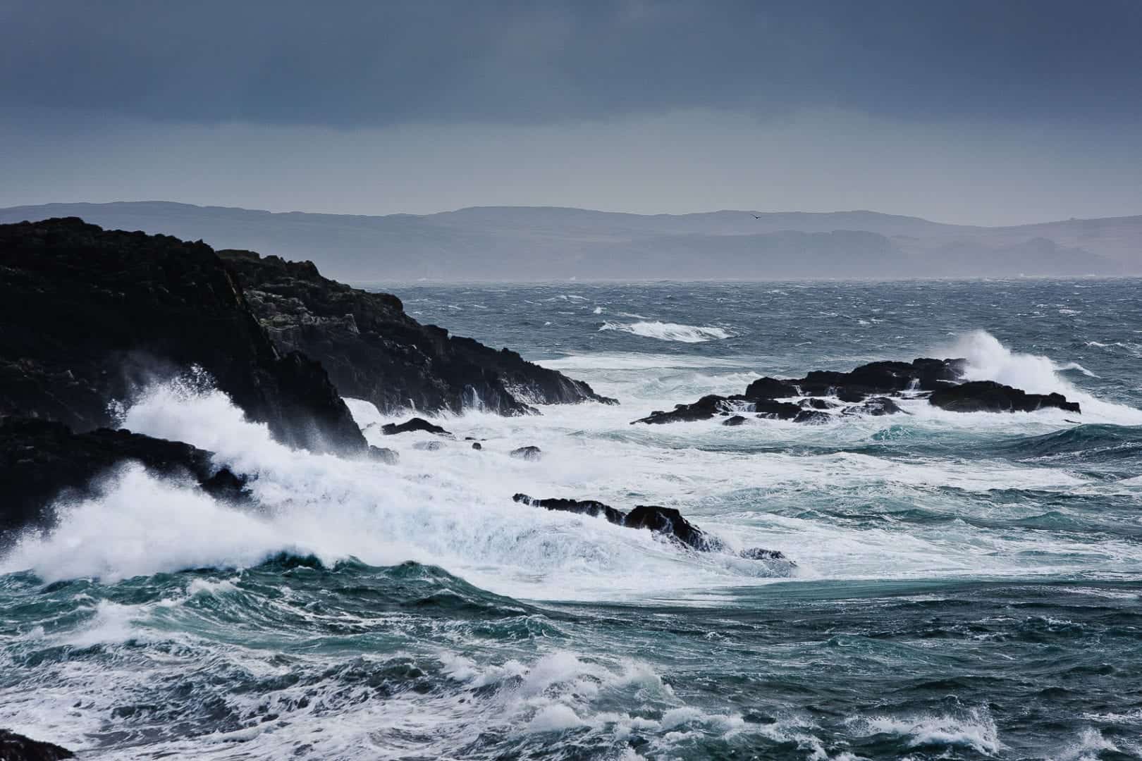 the waves crash against the rocks in port charlotte, islay