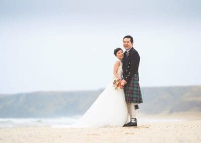 a chinese bride and groom photographed on a beach at their scottish wedding
